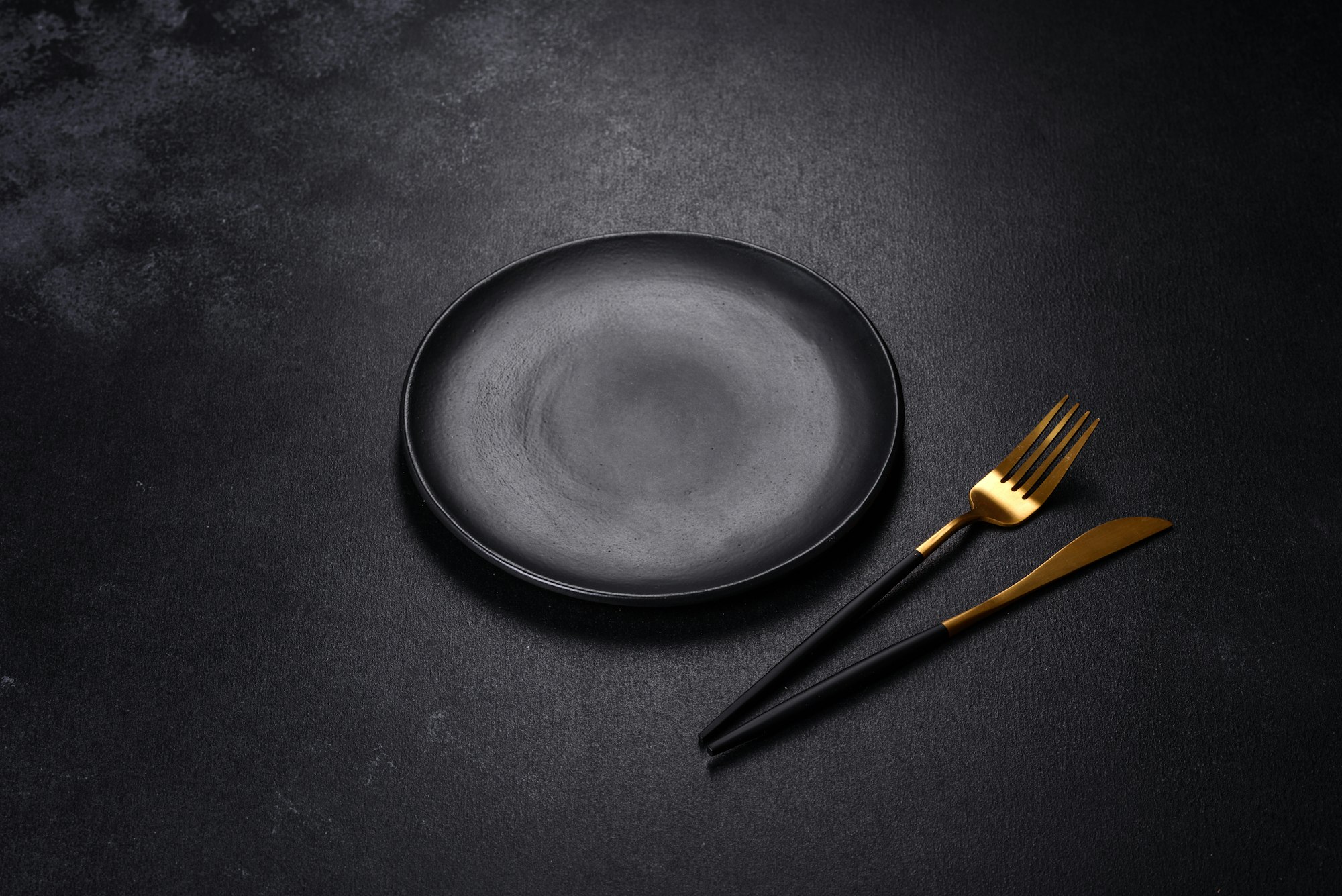 Black plate on a black background. Flat lay, top view, copy space