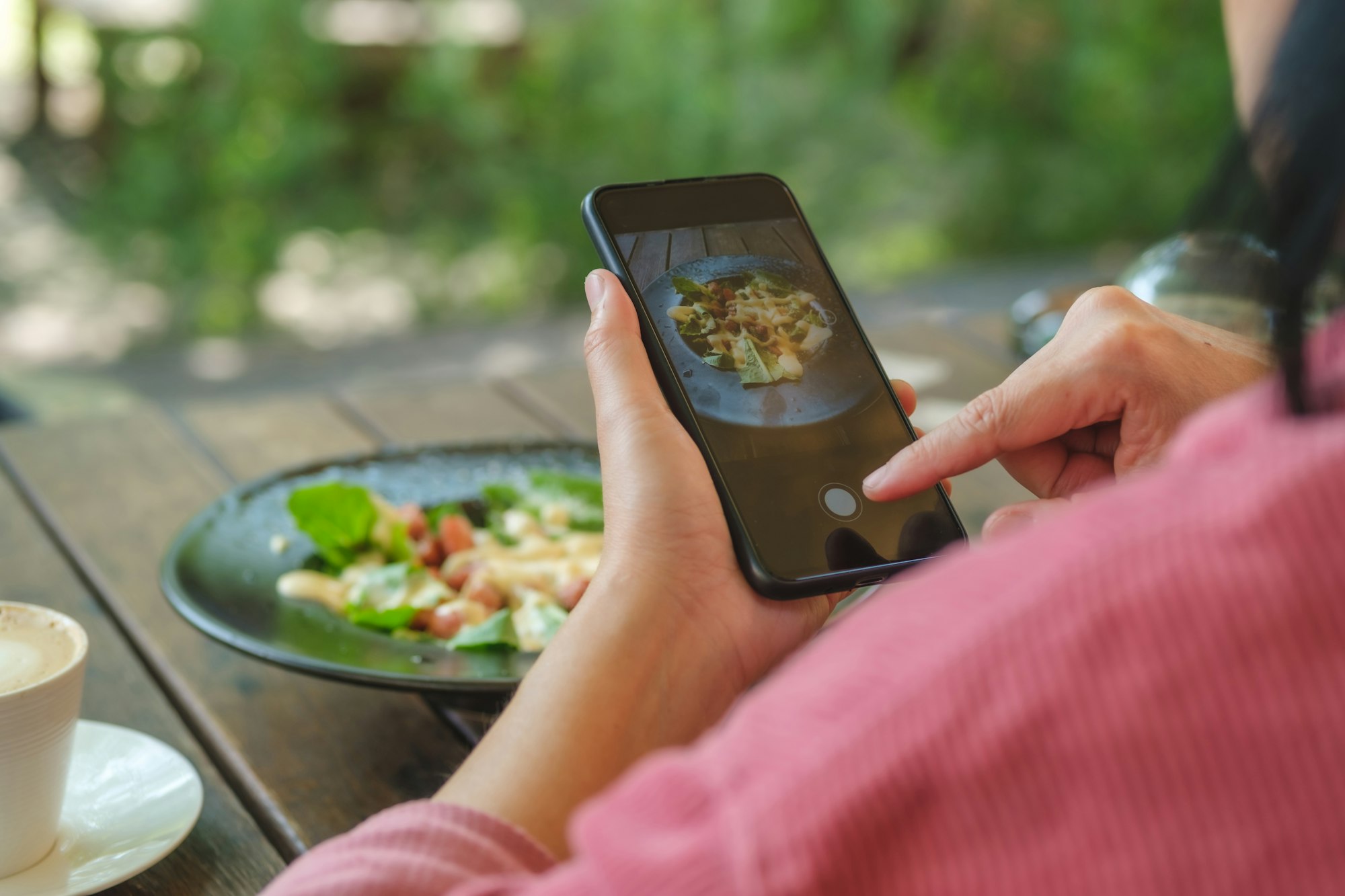 woman use mobile phone take a photo of salad before eating in restaurant